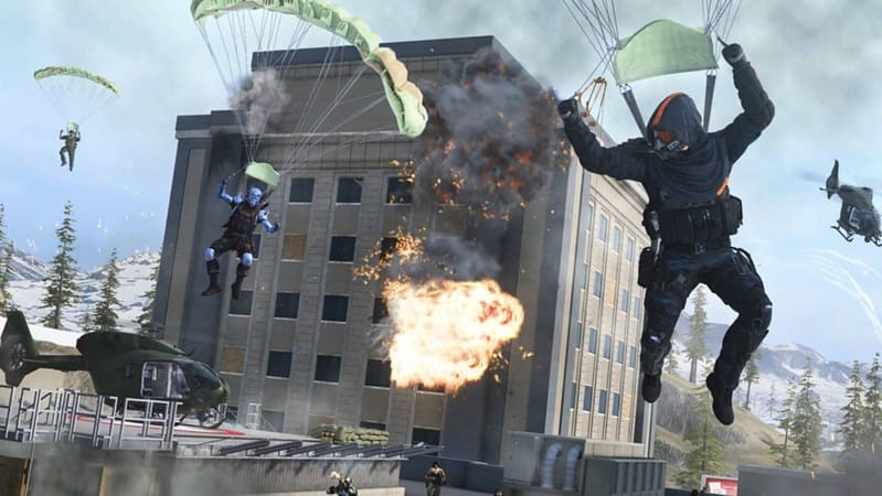 Paratroopers in action amidst an explosion from a building with a helicopter and jet in the background of a warzone.